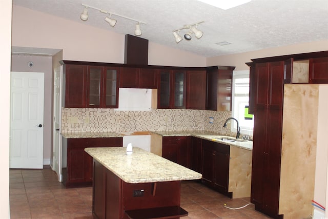 983 Nottingham Lakes Rd, Conway, SC 29526 - kitchen with reddish brown cabinets, decorative backsplash, dark tile patterned floors, a kitchen island, and rail lighting