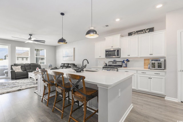312 Cattle Drive Cir, Myrtle Beach, SC 29588 - kitchen featuring stainless steel appliances, light wood-style flooring, decorative backsplash, a kitchen breakfast bar, and recessed lighting