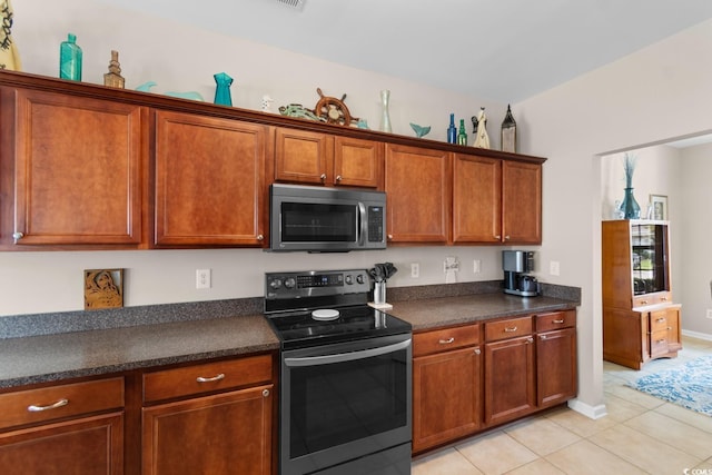 569 Ramblewood Cir, Little River, SC 29566 - kitchen with stainless steel appliances, light tile patterned floors, dark countertops, and brown cabinetry