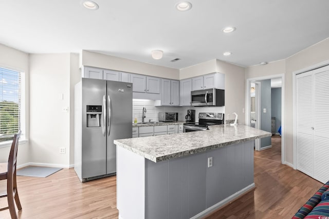 1101 Possum Trot Rd Unit A301, North Myrtle Beach, SC 29582 - kitchen with stainless steel appliances, a peninsula, gray cabinetry, light countertops, and light wood-style flooring