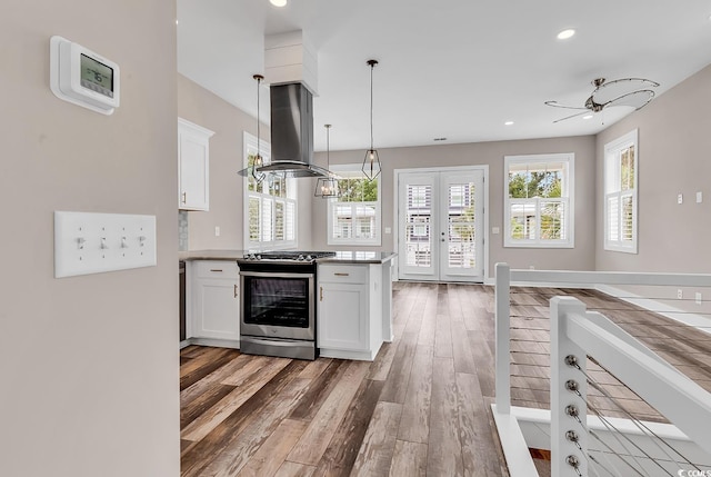 202 Clam Digger Loop, Pawleys Island, SC 29585 - kitchen with gas range, range hood, light wood-type flooring, a peninsula, and white cabinets