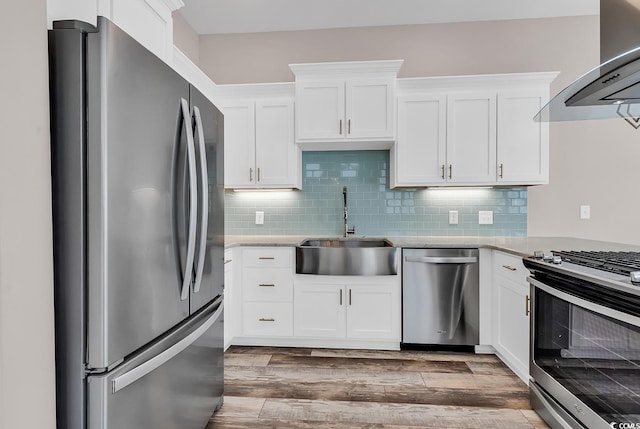 202 Clam Digger Loop, Pawleys Island, SC 29585 - kitchen featuring stainless steel appliances, wall chimney exhaust hood, white cabinetry, wood finished floors, and backsplash