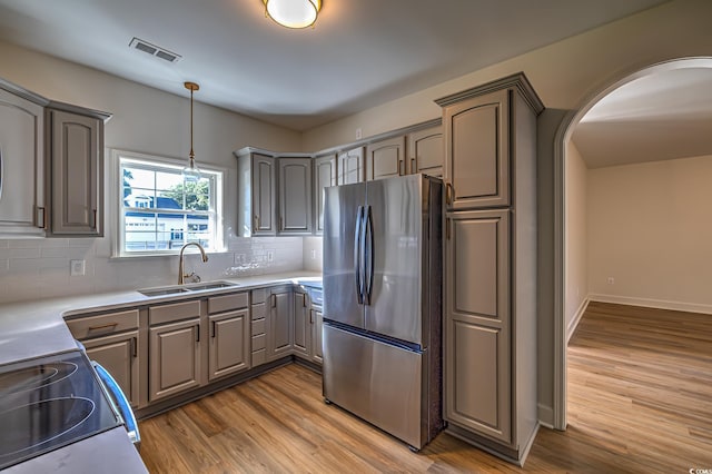 4000 Bayfield Loop, Murrells Inlet, SC 29576 - kitchen featuring freestanding refrigerator, gray cabinetry, wood finished floors, arched walkways, and decorative backsplash