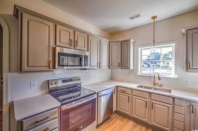 4000 Bayfield Loop, Murrells Inlet, SC 29576 - kitchen featuring appliances with stainless steel finishes, hanging light fixtures, tasteful backsplash, light wood-style flooring, and light countertops