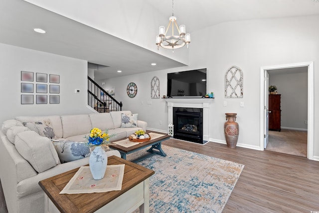 3909 On Deck Cir, Little River, SC 29566 - living room featuring wood finished floors, a chandelier, stairs, a glass covered fireplace, and high vaulted ceiling