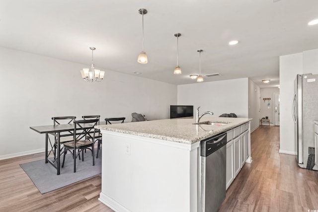 1117 Fairway Ln Unit 1117, Conway, SC 29526 - kitchen with stainless steel appliances, light wood-style flooring, hanging light fixtures, a center island with sink, and light stone countertops