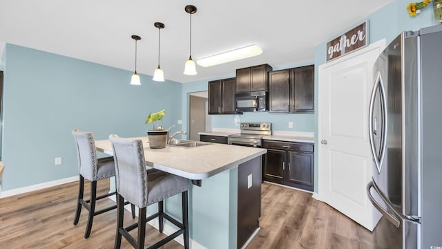 1201 Midtown Village Dr, Conway, SC 29526 - kitchen featuring appliances with stainless steel finishes, dark brown cabinetry, a breakfast bar, and light countertops
