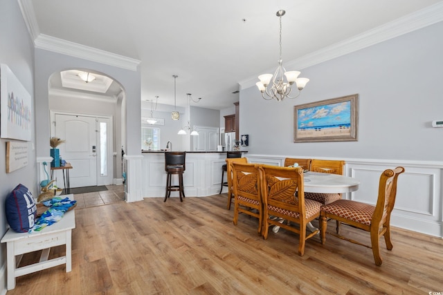 265 Venice Way Unit 1-404, Myrtle Beach, SC 29577 - dining area with crown molding, arched walkways, light wood finished floors, a chandelier, and a decorative wall