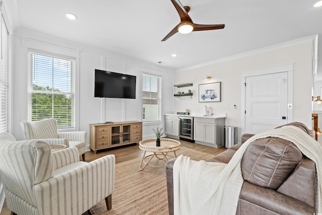 304 29th Ave N, North Myrtle Beach, SC 29582 - living room featuring beverage cooler, bar with sink, ornamental molding, light wood-style floors, and ceiling fan