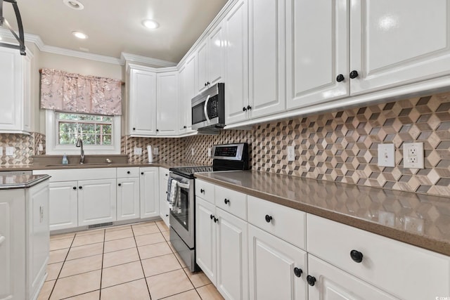1504 27th Ave N, North Myrtle Beach, SC 29582 - kitchen featuring stainless steel appliances, crown molding, white cabinetry, light tile patterned flooring, and decorative backsplash