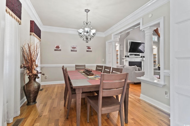 1504 27th Ave N, North Myrtle Beach, SC 29582 - dining area featuring ornamental molding, light wood finished floors, a fireplace, ornate columns, and a chandelier