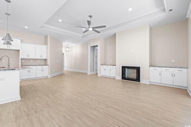 293 Waterfall Cir, Little River, SC 29566 - unfurnished living room featuring a raised ceiling, light wood finished floors, recessed lighting, a glass covered fireplace, and ceiling fan