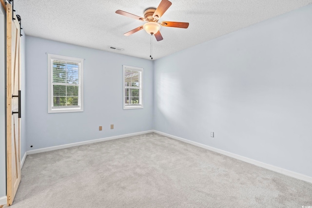 603 Bucks Trl, Longs, SC 29568 - spare room with light colored carpet, a textured ceiling, a barn door, and a ceiling fan