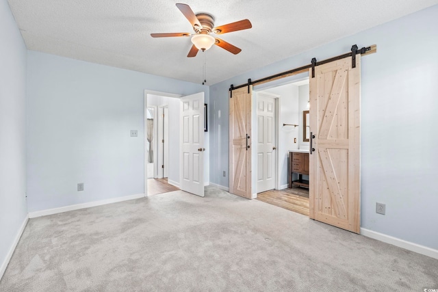 603 Bucks Trl, Longs, SC 29568 - unfurnished bedroom featuring a barn door, carpet flooring, ensuite bathroom, and ceiling fan