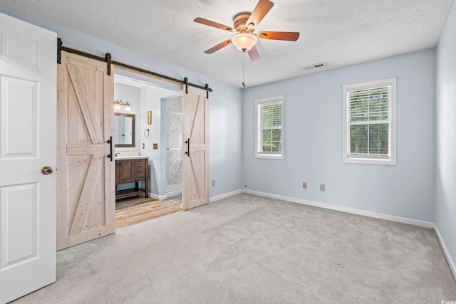 603 Bucks Trl, Longs, SC 29568 - unfurnished bedroom with a barn door, carpet floors, a textured ceiling, ensuite bathroom, and a ceiling fan