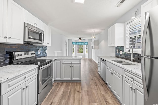 603 Bucks Trl, Longs, SC 29568 - kitchen with appliances with stainless steel finishes, a peninsula, light wood-type flooring, decorative backsplash, and white cabinetry