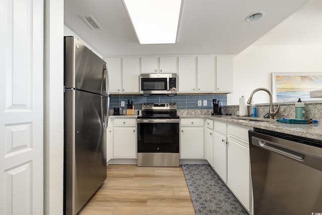 2701 S Ocean Blvd Unit 1908, North Myrtle Beach, SC 29582 - kitchen featuring appliances with stainless steel finishes, white cabinets, light wood-style floors, decorative backsplash, and light stone counters