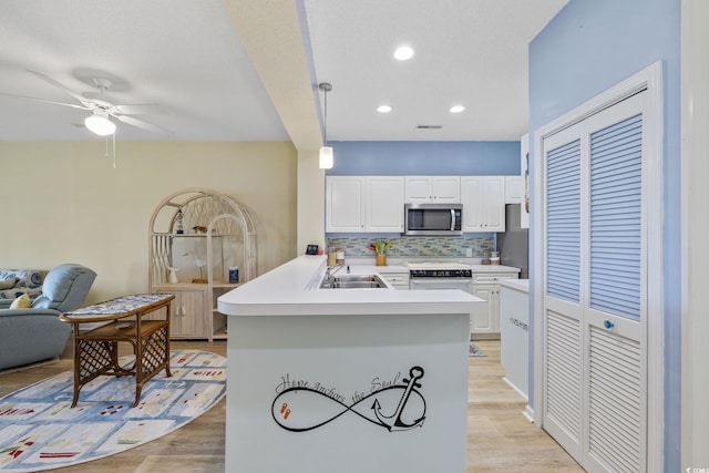 4430 Turtle Ln Unit 2-C, Little River, SC 29566 - kitchen featuring stainless steel microwave, a peninsula, open floor plan, ceiling fan, and white cabinetry