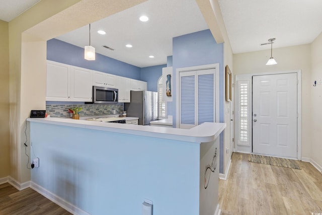 4430 Turtle Ln Unit 2-C, Little River, SC 29566 - kitchen with stainless steel appliances, light wood finished floors, decorative backsplash, white cabinetry, and a peninsula