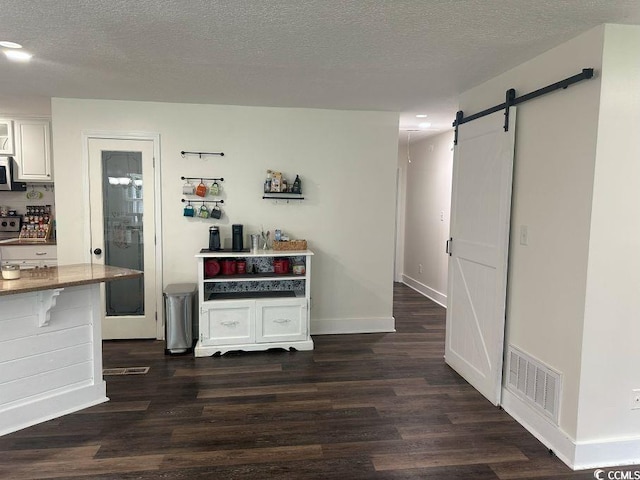 214 Rum Bluff Blvd, Longs, SC 29568 - kitchen featuring a barn door, dark wood-style floors, stainless steel microwave, white cabinets, and a textured ceiling