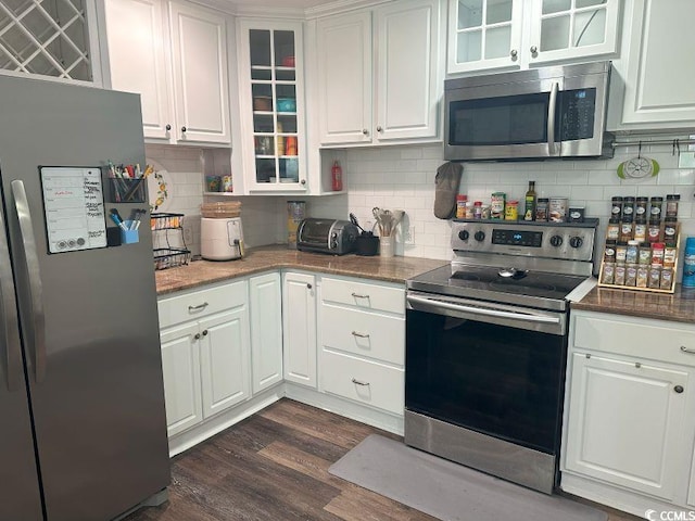 214 Rum Bluff Blvd, Longs, SC 29568 - kitchen with stainless steel appliances, white cabinetry, dark wood finished floors, tasteful backsplash, and glass insert cabinets