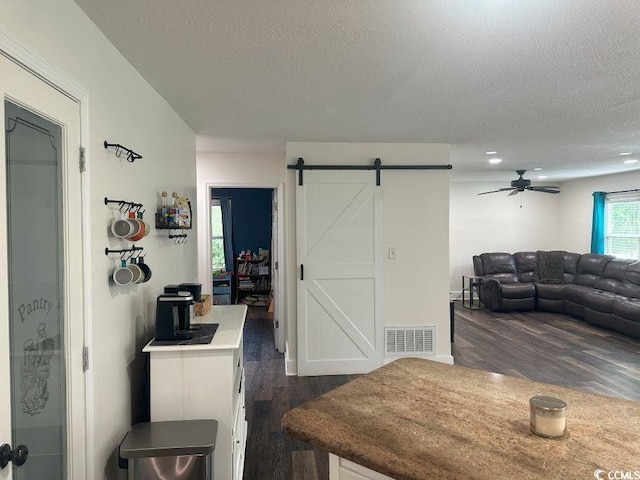 214 Rum Bluff Blvd, Longs, SC 29568 - dining area featuring a barn door, a textured ceiling, dark wood-type flooring, and a ceiling fan