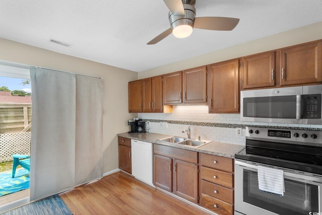 1011 Hunter Ave Unit 1, North Myrtle Beach, SC 29582 - kitchen featuring appliances with stainless steel finishes, brown cabinetry, light wood-style floors, and backsplash