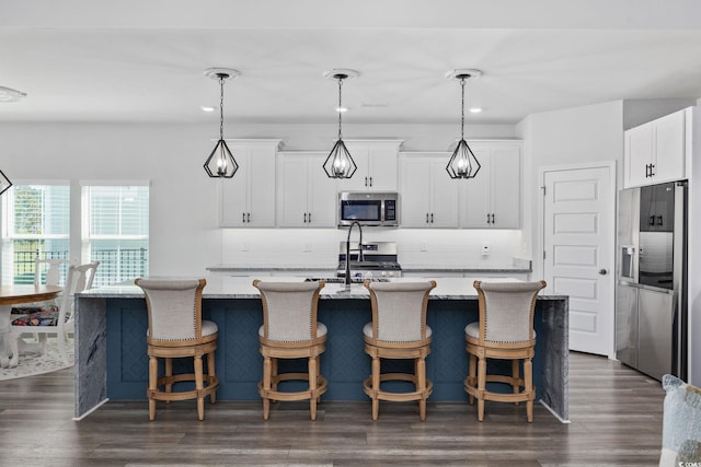 5540 Whitebark Dr, Myrtle Beach, SC 29577 - kitchen with stainless steel appliances, tasteful backsplash, a kitchen bar, white cabinetry, and recessed lighting