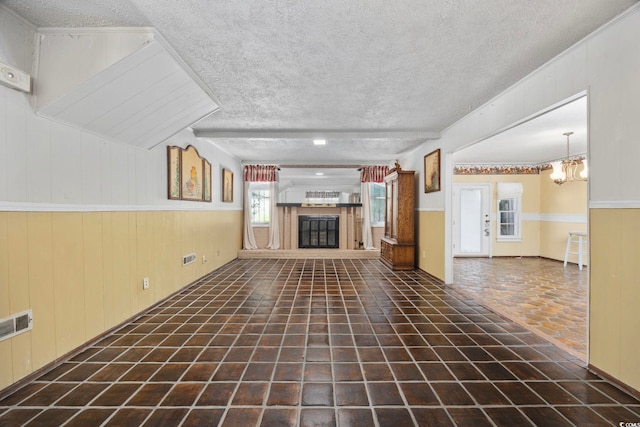 708 Charlotte Rd, Myrtle Beach, SC 29577 - unfurnished living room with a textured ceiling, a glass covered fireplace, a chandelier, and wood walls