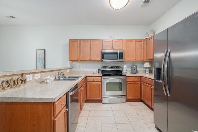 6253 Catalina Dr Unit 1113, North Myrtle Beach, SC 29582 - kitchen featuring appliances with stainless steel finishes, a peninsula, light countertops, light tile patterned floors, and brown cabinetry