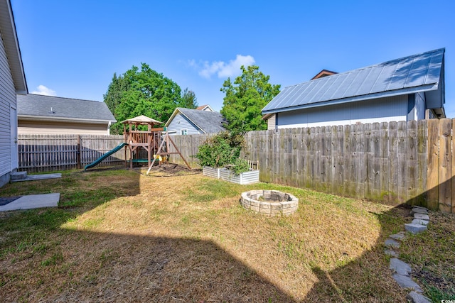 1315 Melanie Ln, Myrtle Beach, SC 29577 - fenced backyard featuring a playground, a vegetable garden, and a fire pit