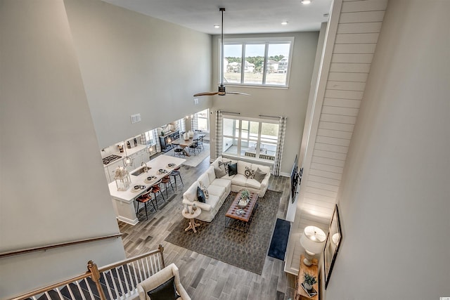 living room with light hardwood / wood-style floors, ceiling fan, and a towering ceiling