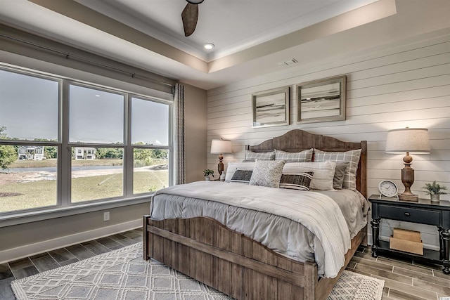 bedroom featuring dark hardwood / wood-style flooring, ceiling fan, and a raised ceiling