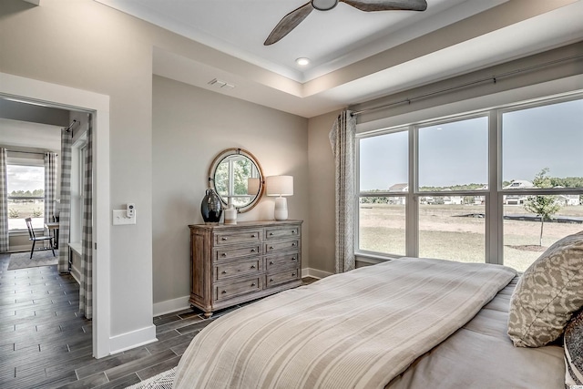 bedroom featuring dark hardwood / wood-style flooring, ceiling fan, and multiple windows