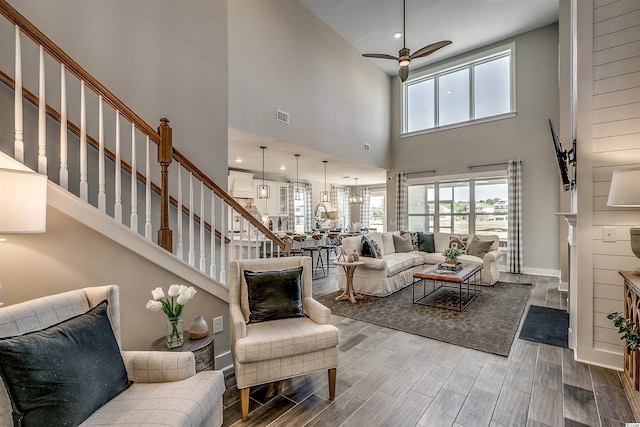 living room with dark hardwood / wood-style floors, ceiling fan, and a towering ceiling