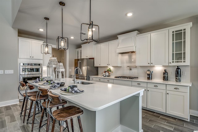 kitchen with tasteful backsplash, white cabinetry, a kitchen bar, premium range hood, and hanging light fixtures