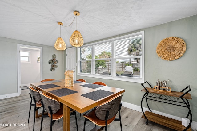 dining area featuring light wood-type flooring, plenty of natural light, and vaulted ceiling