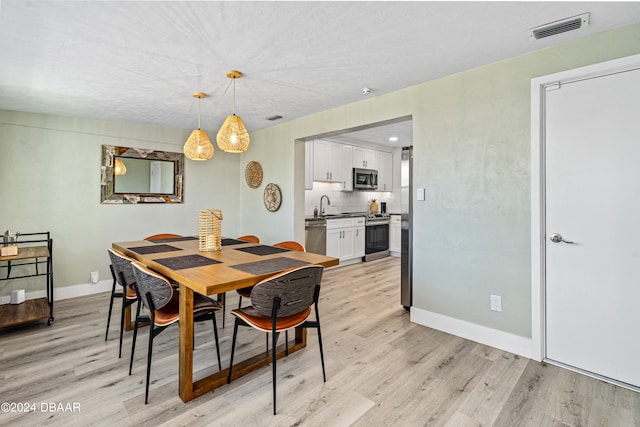 dining space with sink and light hardwood / wood-style floors