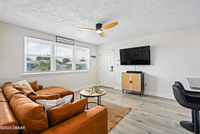 living room featuring ceiling fan, a textured ceiling, and light wood-type flooring