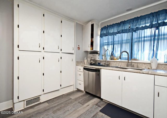 kitchen with visible vents, stainless steel dishwasher, wood finished floors, white cabinets, and a sink