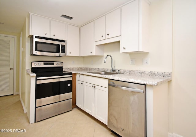 kitchen featuring light tile patterned floors, visible vents, a sink, stainless steel appliances, and white cabinets