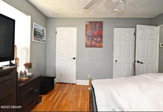 bedroom with baseboards, light wood-style floors, a ceiling fan, and a textured ceiling