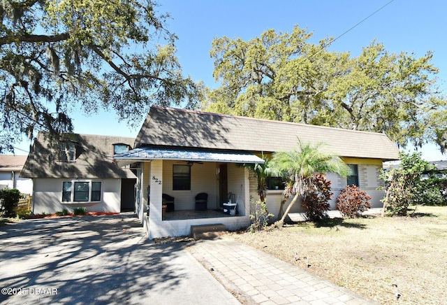 view of front of house featuring a porch, a shingled roof, and mansard roof