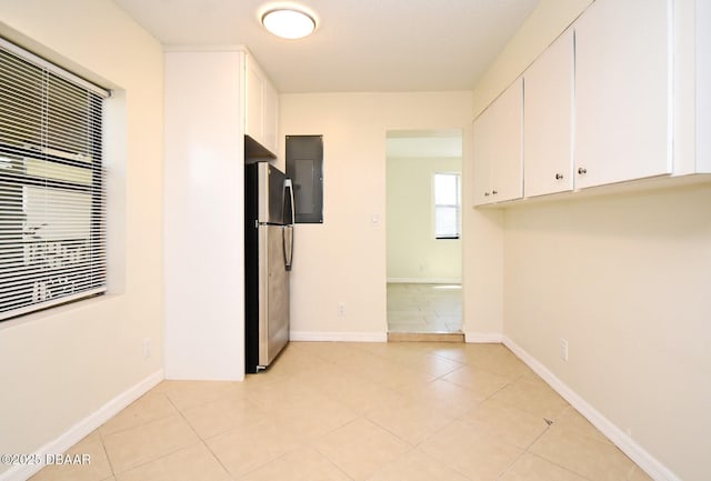 spare room featuring light tile patterned flooring and baseboards