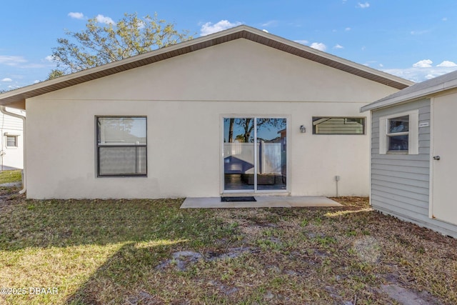 rear view of house with a lawn and stucco siding