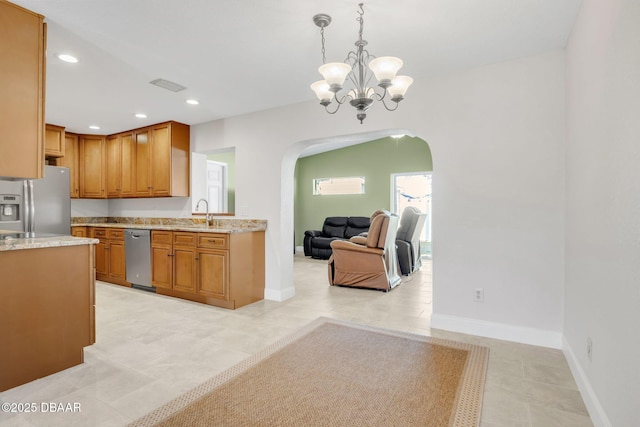 kitchen with arched walkways, brown cabinetry, stainless steel appliances, a chandelier, and recessed lighting