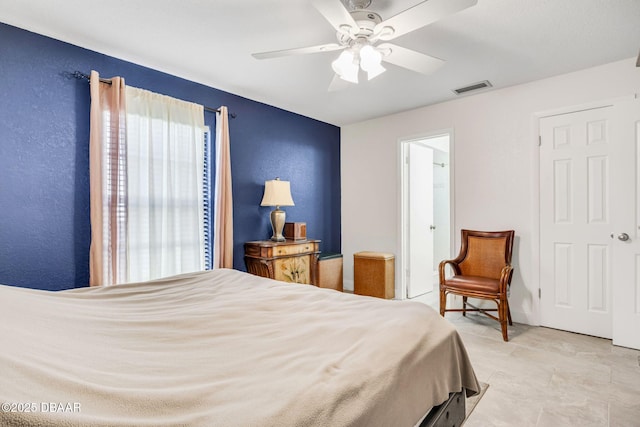 bedroom featuring a ceiling fan, visible vents, and a textured wall