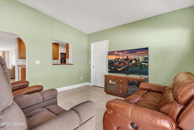 living area with baseboards, arched walkways, and vaulted ceiling