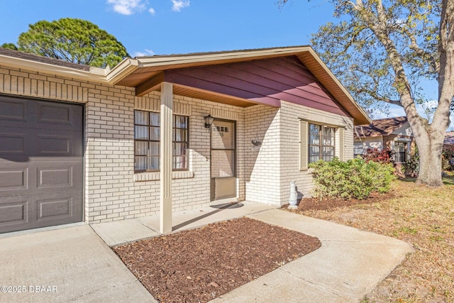 doorway to property featuring a garage and brick siding