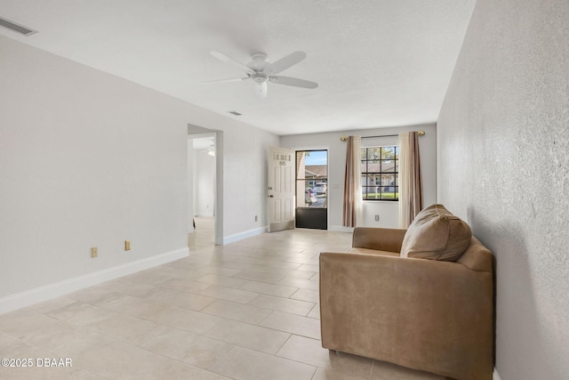 living area with ceiling fan, visible vents, and baseboards